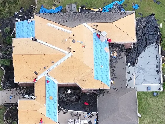 Overhead view of a two-story home with the old roof removed down to new decking and underlayment
