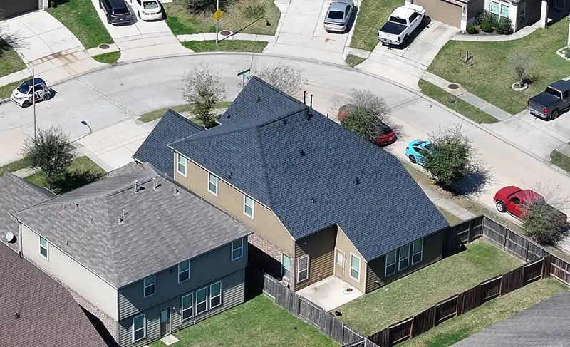 Two-story home with a completed dark shingle roof, drone view, Houston area