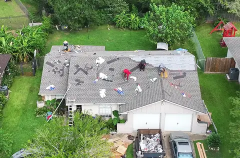 Crew installing new shingles on the same single-story home with a two-car garage
