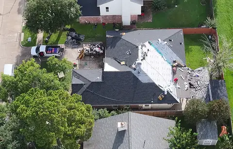 3 S Roofing crew installing dark shingles on a brick home in the Houston area