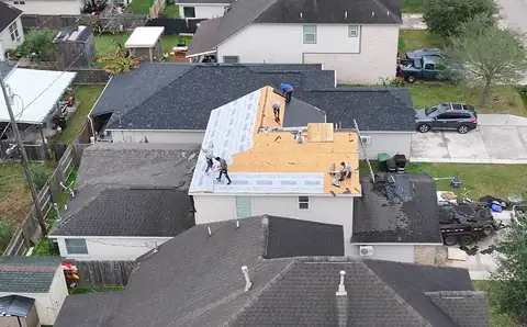 Two-story home with new decking and underlayment on the upper roof and the crew at work