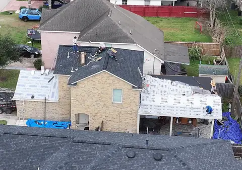 Underlayment on the lower roofs and new shingles going on the upper roof of the same two-story home