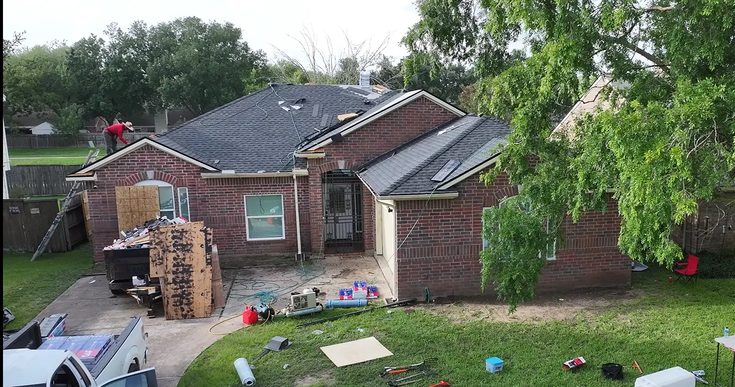 3 S Roofing roofer installing new shingles on a one-story brick home in the Houston area, with old decking stacked for removal