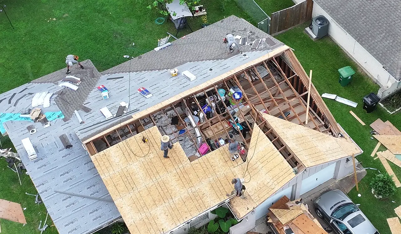 3 S Roofing crew installing new roof decking over exposed rafters on one section of a home