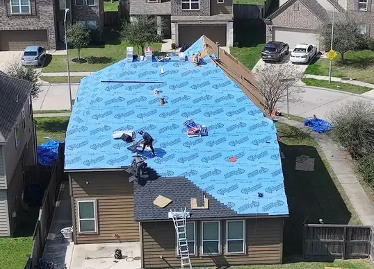 Synthetic underlayment installed and roofing crew actively working during installation