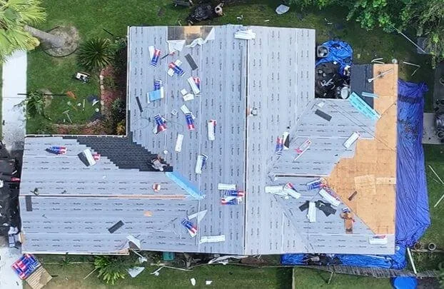 Active shingle installation with decking partially exposed, aerial view, Houston, TX