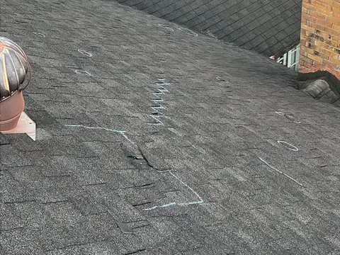 Chalk marks circling areas on an older shingle roof during an inspection