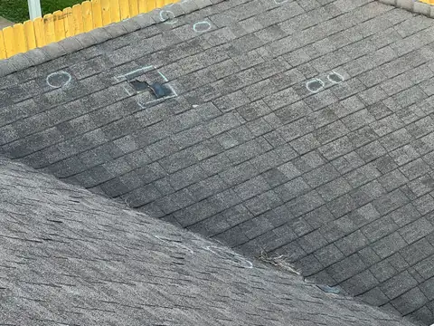 Missing and lifted shingles with chalk marks, documented during a roof inspection