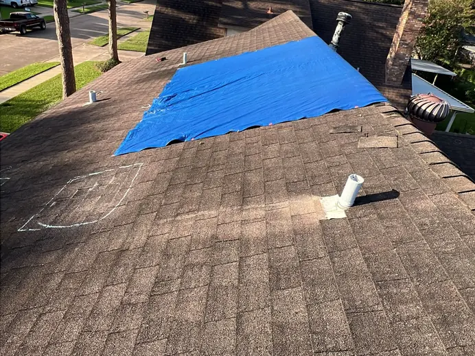 Roof with a temporary tarp over one section and a test area marked in chalk during an inspection