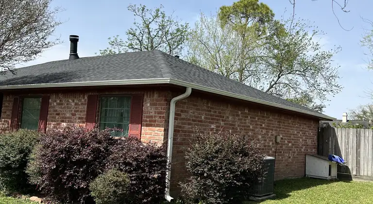 Brick home with red shutters, white gutters and a downspout