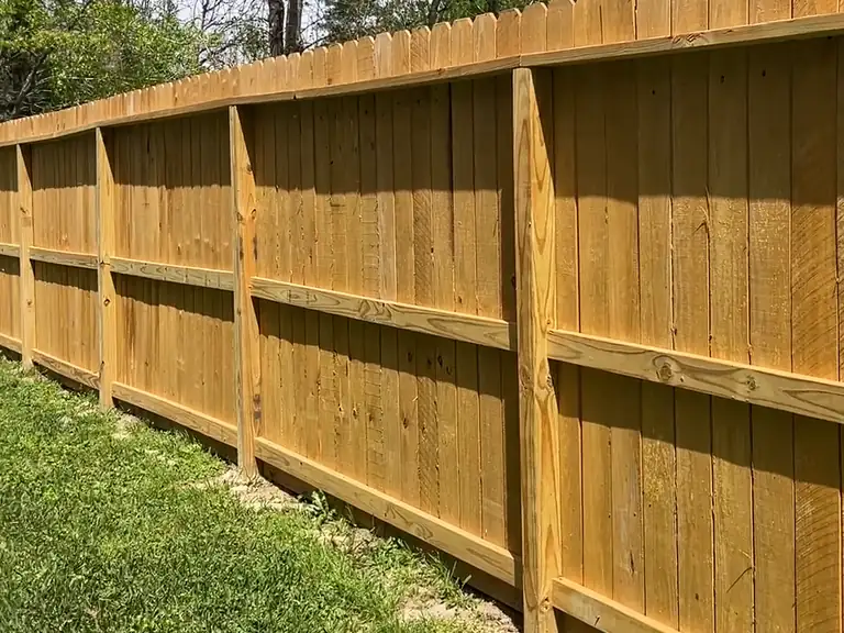 New wood privacy fence running along a backyard